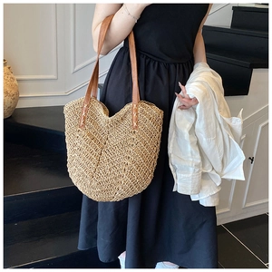 Detail of V-shaped woven straw bag with premium brown leather handle and reinforced stitching