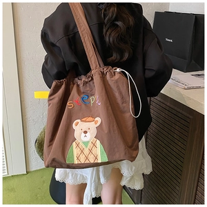 Detail of dark brown tote bag with drawstring closure and colorful cartoon bear embroidery
