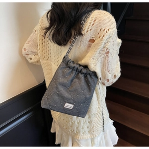 Detail of grey quilted bucket bag with silver studs and chain strap on a model