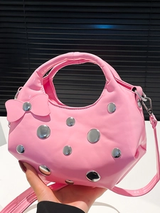 Pink crescent handbag with silver metal studs and bow detail, shown with shoulder strap