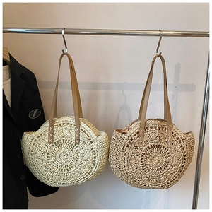 Detail of round straw tote bags in beige and khaki showing woven texture and leather straps