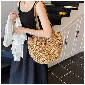 Detail of hand-woven straw tote with hollow round pattern and brown leather straps