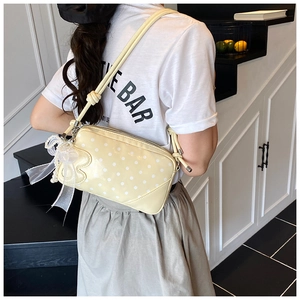 Close-up of yellow polka dot baguette bag with lace bow and pearl pendant detail