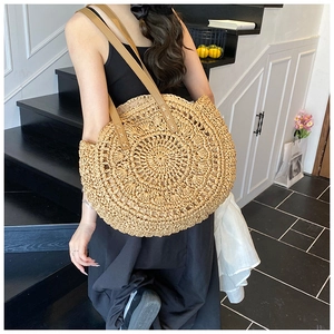 Detailed macro view of large circular woven straw tote bag with brown PU leather straps