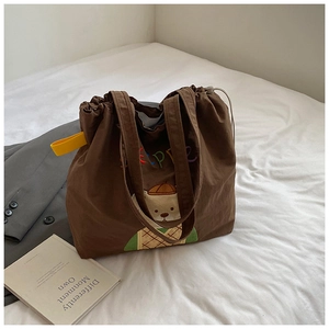 Detail of a brown canvas tote bag with bear embroidery and rainbow drawstring closure
