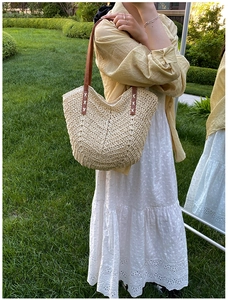 Detail of hand-woven straw tote bag featuring brown leather handles and rich wave texture