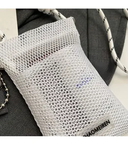 Detailed macro view of white honeycomb mesh phone bag with woven strap and logo label