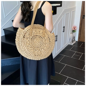 Detail of round straw tote bag with brown leather straps and woven radial texture