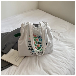 Detail of white tote bag with Tea Time floral print and drawstring closure on bed