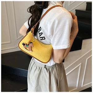 Detail view of yellow fabric shoulder bag with brown leather trim and horse charm
