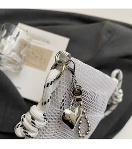Detail of white mesh phone bag with silver heart charm and black-white rope handle