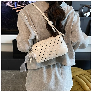 Detail of white polka dot baguette bag with pearl lace charm and embossed texture