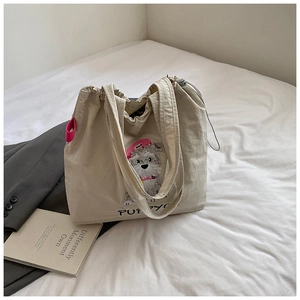 Detail of cream drawstring tote bag featuring schnauzer embroidery and puppy text design
