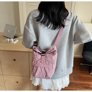 Vue détaillée du sac bandoulière en nylon rose avec cordon et boucle sur un mannequin