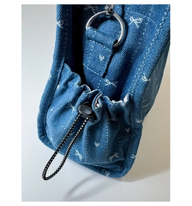 Macro detail of denim bag side showing drawstring closure and silver metal ring connector