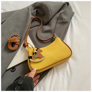 Detail of yellow hobo bag with brown leather trim, wooden horse charm and extra strap