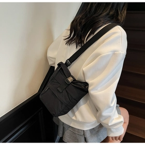 Détail du sac bandoulière en nylon noir avec boucle et large sangle porté par un mannequin