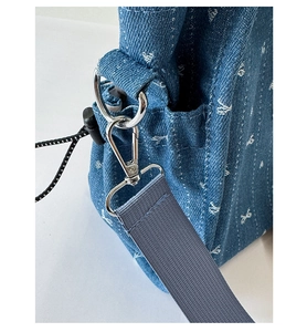 Close-up of blue denim tote bag showing silver metal lobster clasp and heart jacquard pattern