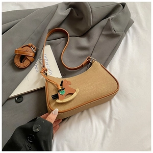 Close-up of crescent-shaped canvas shoulder bag with wooden rocking horse charm detail