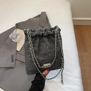 Close-up of charcoal grey quilted bucket bag with silver studs and chain strap