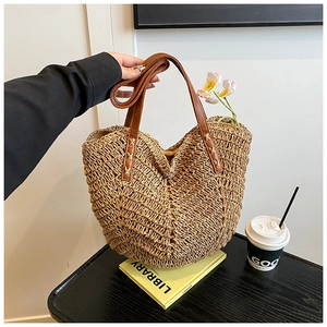 Detail of hand-woven straw tote with brown leather strap and stylish V-neck opening