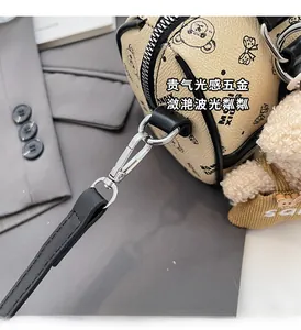 Close-up of beige barrel bag with cartoon bear prints and silver metal hardware