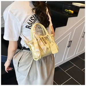 Detail of yellow cross-body bag featuring a checkered scarf handle and brand tag