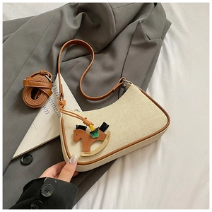 Detail of canvas shoulder bag with brown leather trim and wooden horse charm decoration