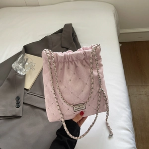 Pink quilted bucket bag detail with silver studs and chain strap held against a blazer