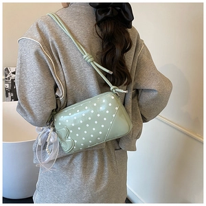 Detail view of mint green polka dot baguette bag with lace pearl charm and 3D butterfly deco