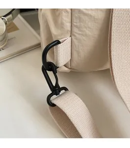 Detail of durable matte black swivel hook and reinforced fabric strap on canvas backpack