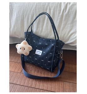 Close-up of dark blue denim tote with white bows, red hearts and a star plush charm