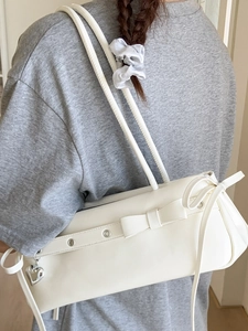 White shoulder bag with bow and silver heart pendant shown on model back view