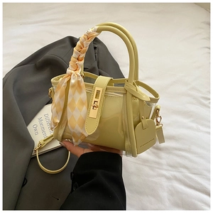 Detail of yellow PVC and patent leather bucket bag with checkered scarf on handle