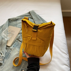 Gros plan d'un sac bandoulière en nylon jaune avec boucle sur un fond de style décontracté