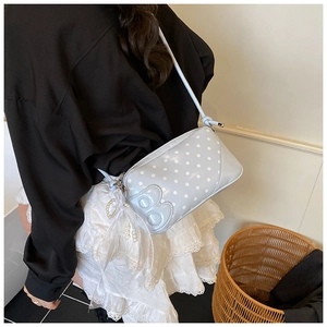 Detail of light blue polka dot baguette bag with white lace bow and pearl charm