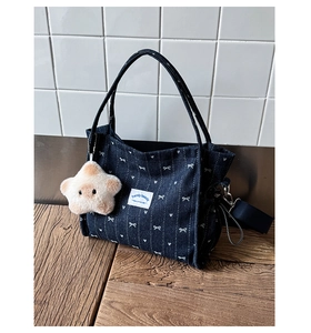 Detail of blue denim tote bag with butterfly prints and a star plush charm