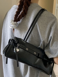 Fashionable black leather shoulder bag for women with silver eyelets and heart charm
