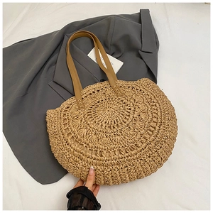 Detail of hand-woven straw tote bag with brown leather handles and circular texture
