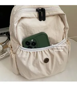 Detail of the cream nylon backpack front pocket with magnetic snap for phone storage