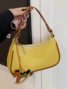 Minimalist yellow woven underarm bag with brown leather straps and wooden horse charm