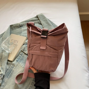 Détail d'un sac bandoulière en nylon rose poudré avec fermeture à boucle et haut roulé