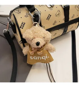 Close-up of a plush bear charm in a yellow dress attached to a beige pillow bag