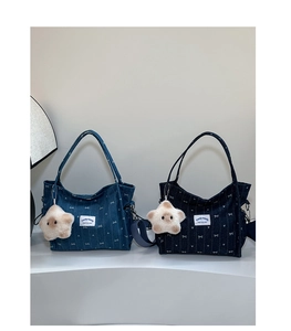 Blue denim tote bags with white bow patterns and plush star charms shown on pedestals