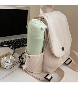 Detail of canvas backpack side pocket with drawstring holding a water bottle
