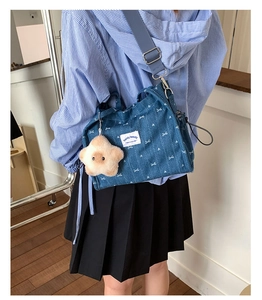 Close-up of denim shoulder bag with white bow patterns and star plush charm accessory