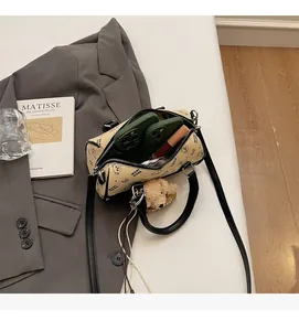 Detail shot of mini beige Boston bag showing spacious interior with phone and lipstick