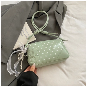 Detail view of mint green polka dot bag with pearl charms and 3D applique on a soft surface