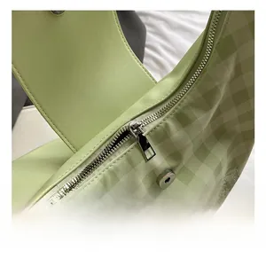 Detail of light green plaid bag showing top metal zipper and magnetic snap closure