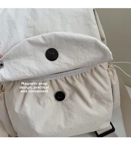Detail view of the magnetic snap closure on a cream canvas backpack showing the fabric texture